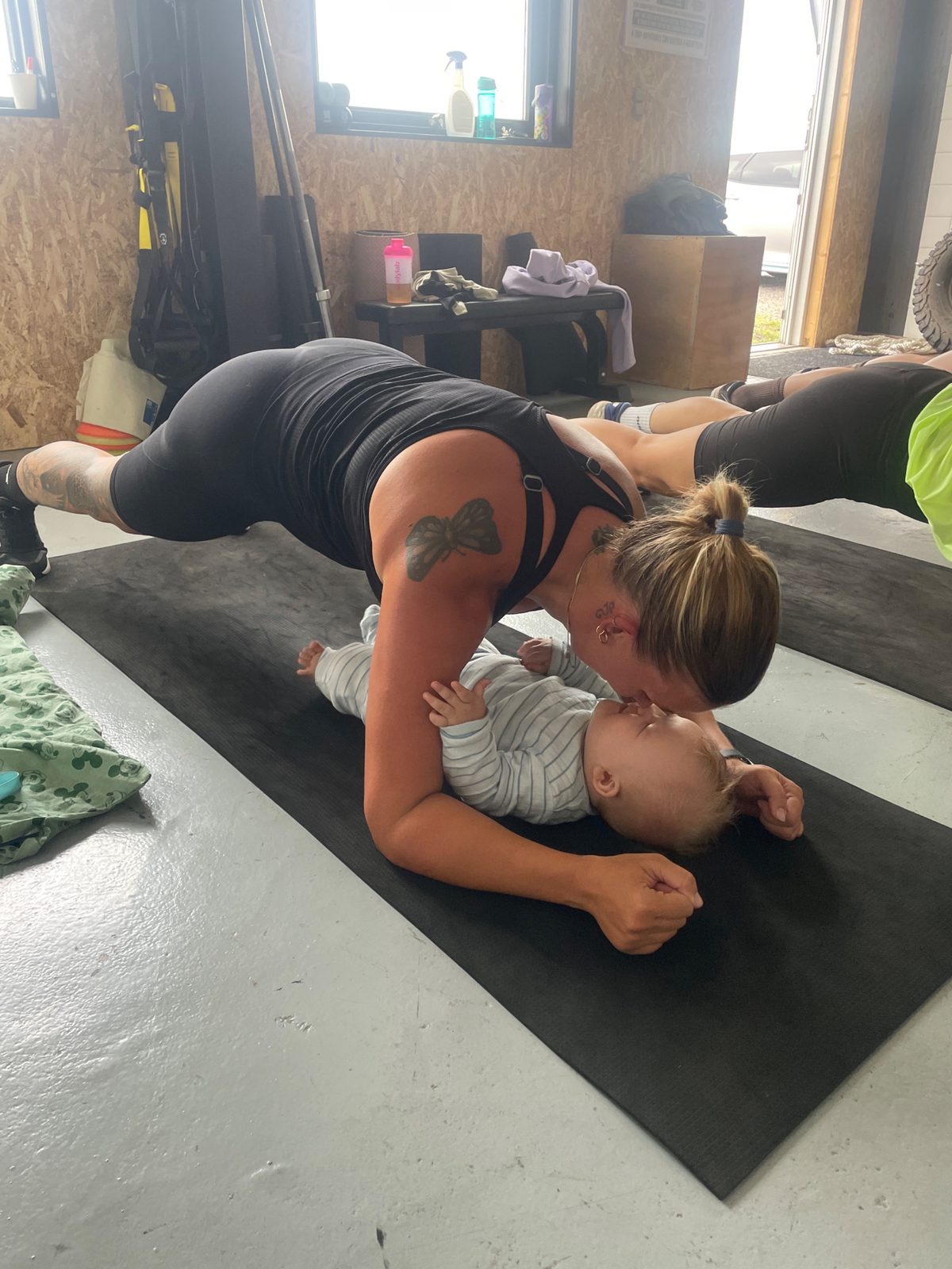 En mor laver planken over sin baby på måtten